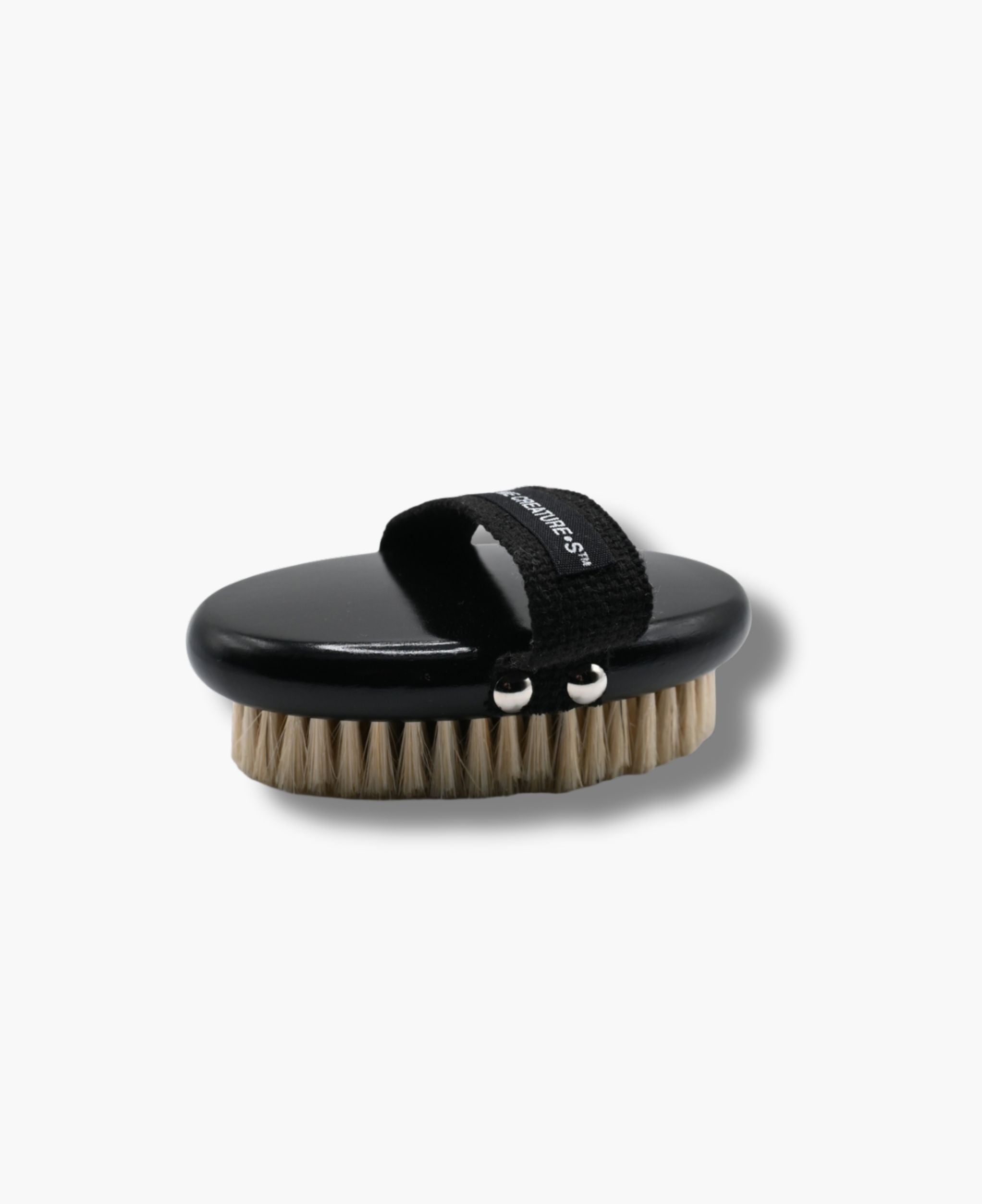 Minimalist body brush with natural bristles and black wooden handle